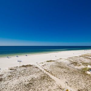 This stunning beachfront view showcases soft white sands and vibrant blue waters, perfect for a relaxing getaway