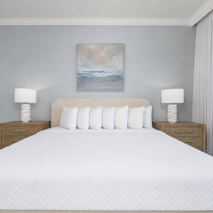 Relax in this serene master bedroom featuring a king bed, stylish lamps, and beach balcony