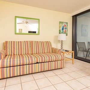 This living area features a colorful striped sofa, a sleek lamp, and a stunning beachfront view through sliding glass doors