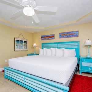 Guest bedroom featuring a bright turquoise queen, cozy pillows, and colorful artwork, creating a cheerful retreat