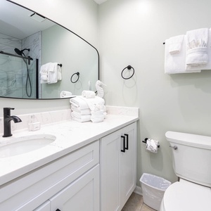 Sleek guest bathroom featuring a spacious vanity with a marbled countertop, a walk-in shower, and fluffy towels