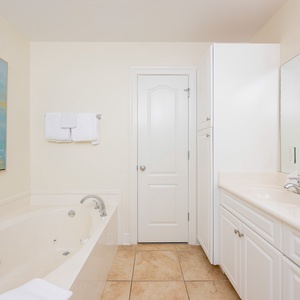 Master bathroom featuring a jetted tub, walk-in shower, elegant vanity, and a beautiful heron painting on the wall