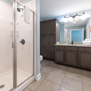Enjoy a relaxing shower after a day at the beach in this guest bath with stylish cabinetry and spacious vanity