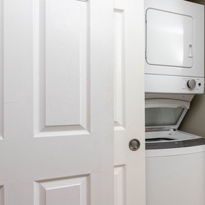 This laundry area features a stacked washer and dryer behind closed white doors, providing convenience for your stay