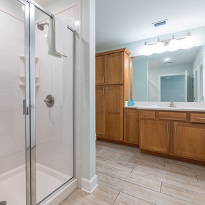 Enjoy a relaxing shower after a day at the beach in this guest bath with stylish accents and fluffy towels