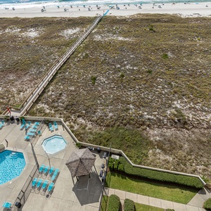 View of the pool area with turquoise lounge chairs, a kiddie pool, and a pathway leading directly to the beach