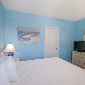 Bright blue walls complement the king bed and decorative accents, creating a serene atmosphere in this inviting guest room