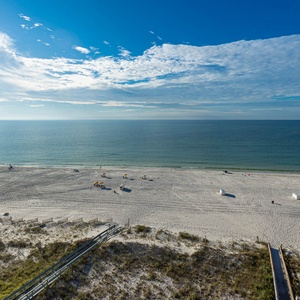Expansive beachfront view showcasing white sand and tranquil waters under a bright blue sky, perfect for relaxation