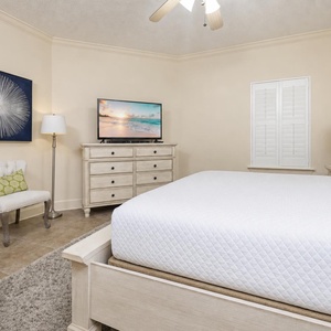 Retreat to the tranquil master bedroom featuring a king bed, a TV, and a cozy chair for relaxation