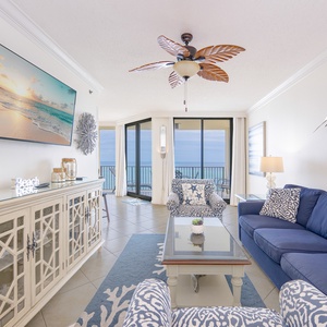 Cozy living area features a navy sofa with queen sleeper, elegant decor, and a view of the balcony overlooking the beach