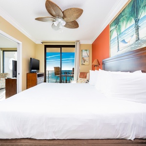 Relax in this inviting master bedroom featuring a king bed, colorful decor, and balcony access with stunning beach views
