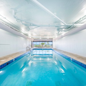 Swim in the indoor pool with a view of palm trees and beach access, perfect for relaxation and fun during your stay