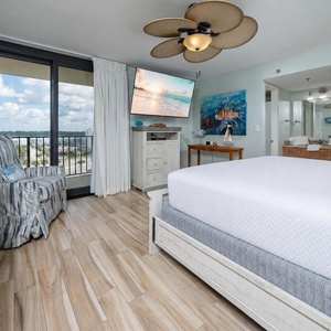 Master suite featuring a cozy chair, large TV, and inviting views through sliding glass doors