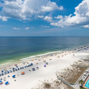 The view showcases a vibrant beach scene with colorful umbrellas dotting the white sand, inviting relaxation and fun