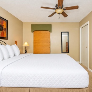 The master bedroom features a plush king bed, a stylish ceiling fan, and warm accent decor for a restful retreat