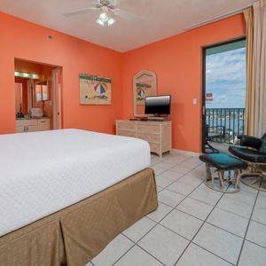 Cozy master bedroom featuring a plush bed, TV, and a balcony with a view of the bay and surrounding area