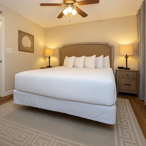 This serene guest bedroom features a king bed with decorative pillows, soft lighting, and elegant gray curtains