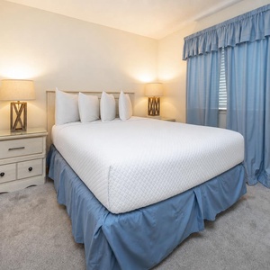 Cozy bedroom featuring a queen bed, soft blue accents, and warm lighting for a restful retreat