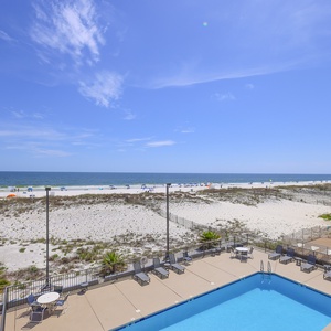 This inviting view showcases a sparkling pool area and a beautiful beachfront, perfect for relaxation and fun