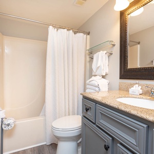 The guest bathroom features a granite countertop, a tub/shower combo, and neatly arranged towels for a refreshing experience
