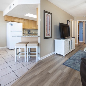 Bright and inviting living area features a comfortable leather chair, a TV, and a breakfast bar with seating