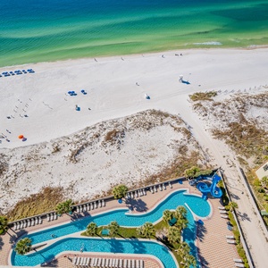 This vibrant beachfront view showcases the lazy river surrounded by lounge chairs and palm trees, perfect for relaxation
