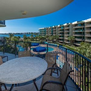 Savor the coastal breeze while lounging at the table, taking in the vibrant pool and bay views below