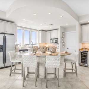 This modern kitchen features stainless appliances, granite countertops, and a scenic beach view from the large windows