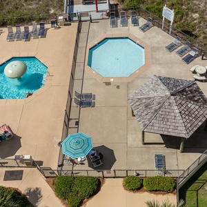 A vibrant pool area features a large swimming pool, a fun water fountain, and shaded seating under a charming gazebo