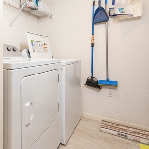 A laundry area features a washer and dryer with cleaning supplies neatly organized on the wall above for convenience
