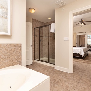 The master bath features a relaxing jetted tub and a glass-enclosed walk-in shower, with a view of the inviting master suite
