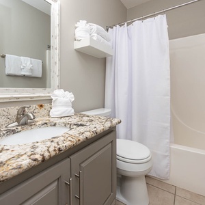 Experience the guest bathroom featuring a granite countertop, modern fixtures, and fresh towels