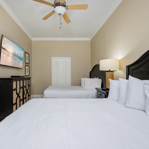 Relaxing guest bedroom featuring two queen beds, a large TV, and coastal decor for a relaxing stay