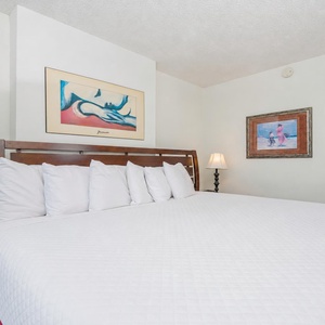 This cozy bedroom features a large king bed with plush pillows, complemented by colorful artwork and soft lighting for relaxation