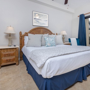 Relax in the inviting king master suite featuring a plush bed, decorative pillows, and access to the beachfront patio