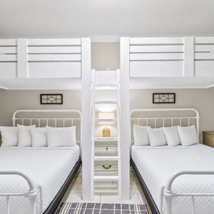 Cozy guest bunk room featuring two queen beds and two twin loft bunks, perfect for family fun