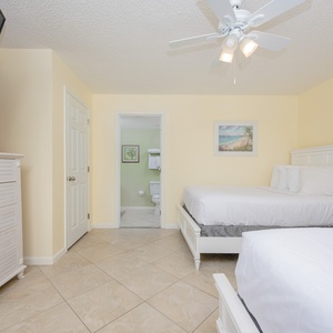 Inviting guest bedroom featuring double beds, a dresser, and an adjoining bathroom
