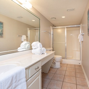 Bright master bathroom featuring a spacious vanity, neatly stacked towels, and a walk-in shower for a refreshing experience