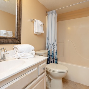 Master bathroom featuring a large mirror, fresh towels, and a tub/shower combo with a decorative shower curtain