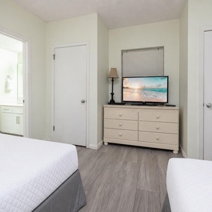 Inviting guest room featuring two double beds, a TV, and easy access to a stylish bathroom