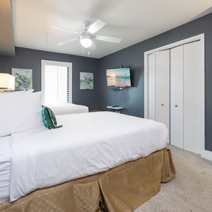 Relax in the guest bedroom featuring two double beds, a TV, and coastal decor for a restful getaway
