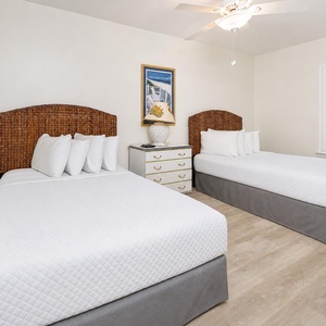 Rest comfortably in this guest bedroom featuring two double beds, stylish decor, and a cheerful vibe for relaxation