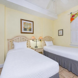 Guest suite with two twin beds offers calm yellow walls and soft lighting for restful nights