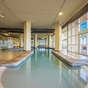Relax by the indoor pool with a view of the beach and palm trees, perfect for unwinding during your stay