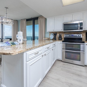 Prepare meals in the spacious kitchen featuring a large breakfast bar, stainless appliances, and beachfront views