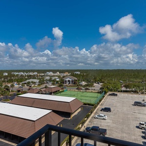 A scenic view from the master showcases a vibrant landscape with tennis courts and lush greenery under a bright blue sky