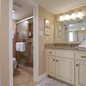 The master bathroom features a glass walk-in shower, vanity with granite countertops, and soft lighting