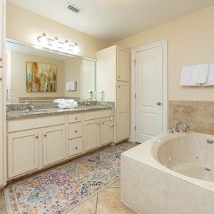 Master bath featuring a jetted tub, walk-in shower, granite countertops, and elegant decor for a relaxing retreat