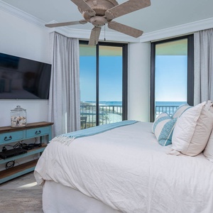Enjoy restful nights in the guest bedroom with a plush king bed, coastal decor, and stunning views through large windows
