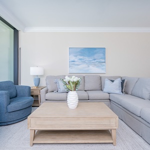 Unwind in the inviting living area, featuring soft seating, queen sofa sleeper, stylish coffee table, and coastal art